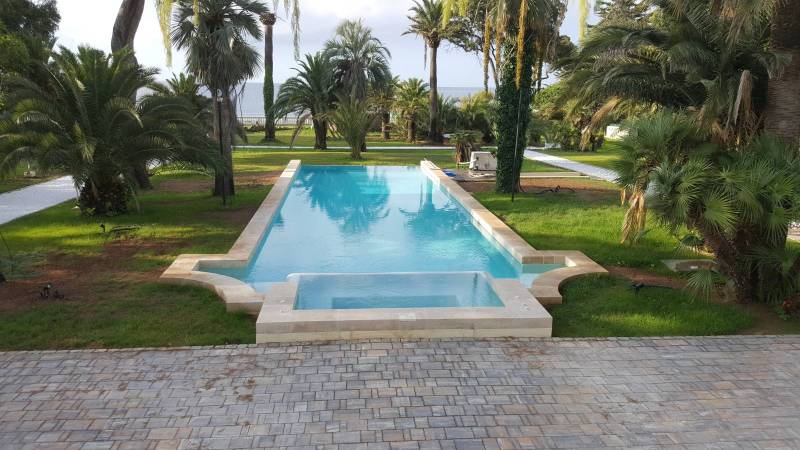 Réalisation d'une piscine couloir de nage haut de gamme de luxe de 15m avec d'un spa débordant en pierre naturelle taillée sur mesure à Cannes Alpes Maritimes 06