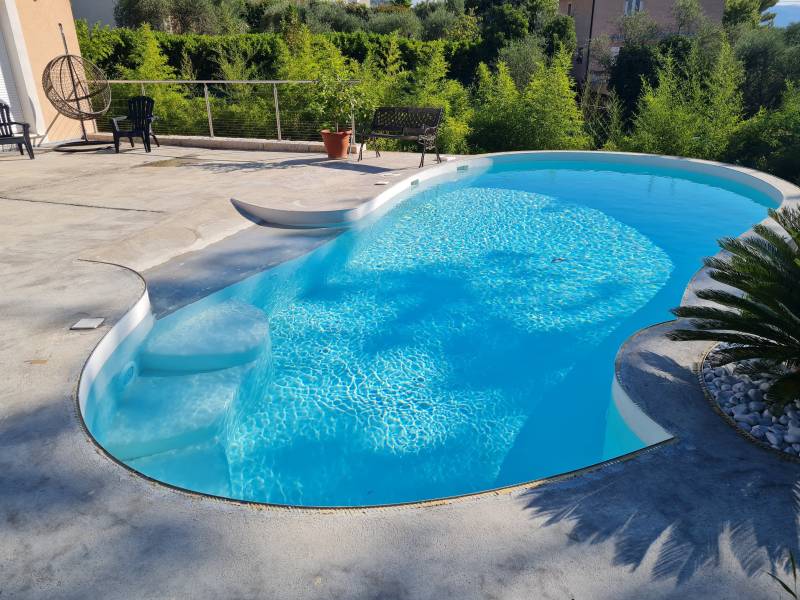 Construction d'une piscine en forme libre de 8mx4 avec terrasse en grain de marbre blanc et plage immergée en bord naturel à La Gaude Alpes Maritimes