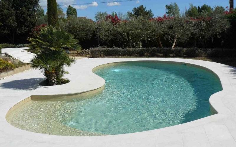 Réalisation d'une piscine en béton armé de forme libre avec sa large plage immergée en émaux de verre beige à Juan les Pins Alpes Maritimes 06 ou ailleurs